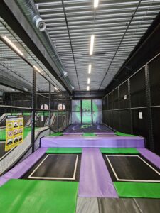 Upgraded trampoline park area with green and purple trampolines leading to an airbag landing zone, offering a safer alternative to traditional foam pits."