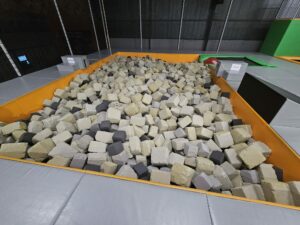 A wide view of a foam pit with unevenly distributed foam blocks, showing how inconsistent cushioning can lead to unpredictable landings and increased risks.